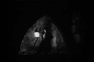 In the dark catacombs a man with a lantern gives the prologue in The Phantom of the Opera, 1925.